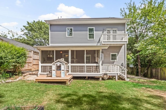 rear view of house with a sunroom, a lawn, and a balcony