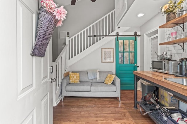 interior space featuring a barn door, ceiling fan, a towering ceiling, and wood-type flooring