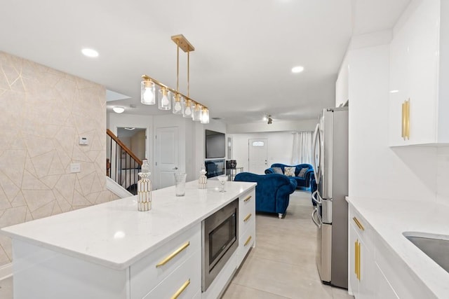 kitchen featuring decorative light fixtures, a kitchen island, appliances with stainless steel finishes, and white cabinetry