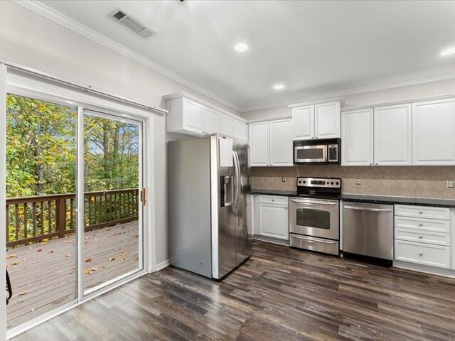 kitchen with white cabinetry, stainless steel appliances, dark wood-type flooring, and crown molding