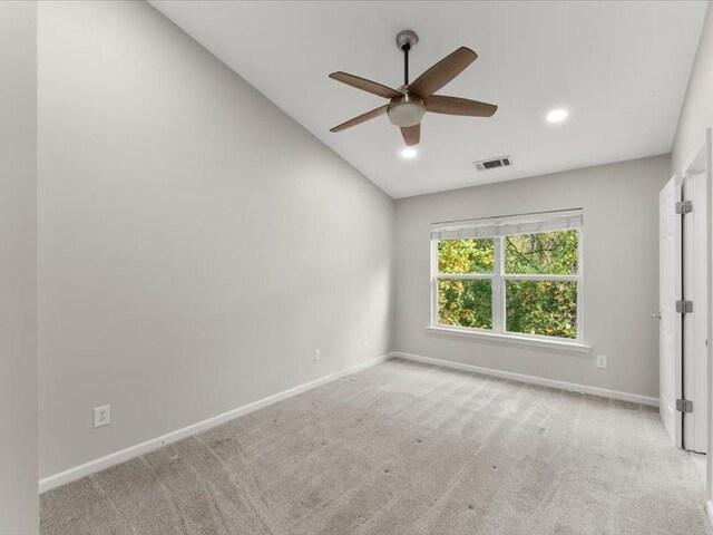 spare room featuring lofted ceiling, light carpet, and ceiling fan