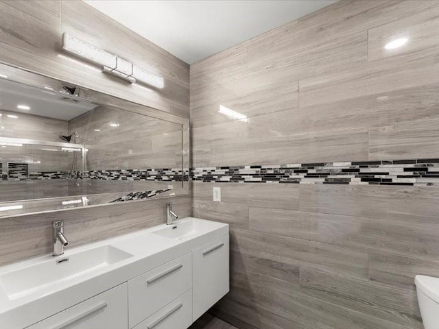 bathroom featuring tile walls, walk in shower, vanity, and toilet