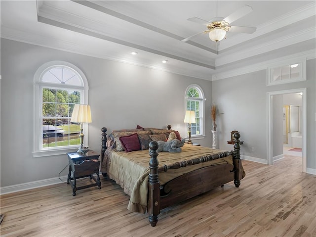 bedroom featuring a tray ceiling, crown molding, and multiple windows