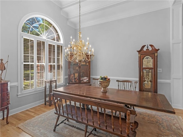 dining space with an inviting chandelier, ornamental molding, and light wood finished floors