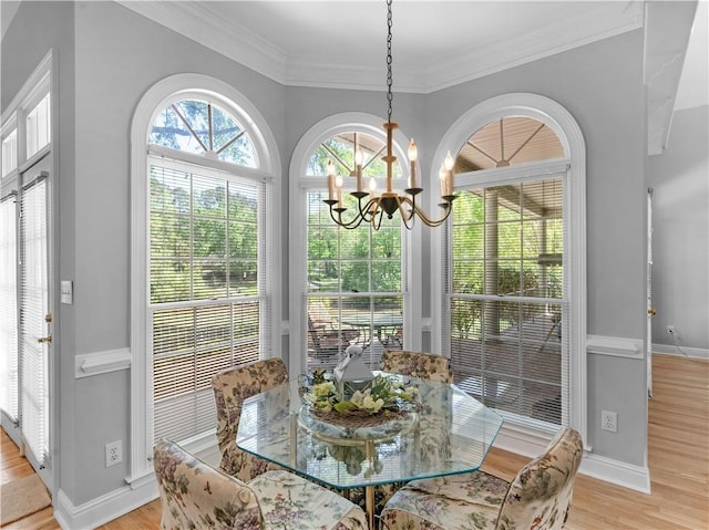 dining space with light wood-type flooring, baseboards, ornamental molding, and an inviting chandelier