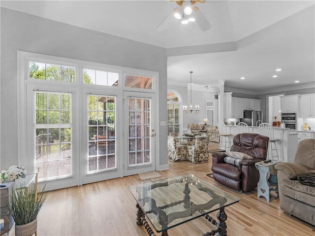 living room featuring recessed lighting, ornamental molding, light wood-style floors, and ceiling fan with notable chandelier