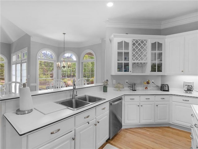 kitchen with a peninsula, dishwasher, a sink, and white cabinetry