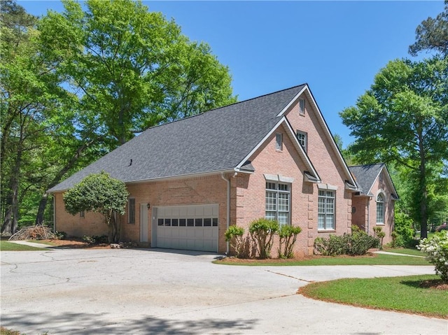 ranch-style home with a garage, brick siding, roof with shingles, and concrete driveway