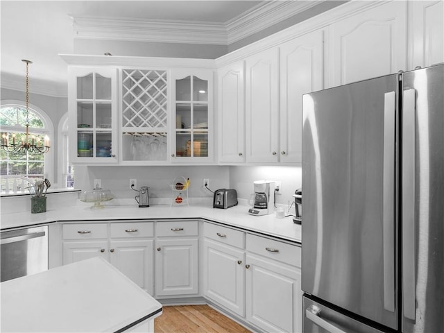 kitchen featuring white cabinetry, glass insert cabinets, crown molding, light countertops, and appliances with stainless steel finishes
