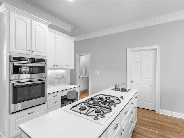 kitchen with white cabinets, white gas stovetop, stainless steel double oven, light countertops, and ornamental molding