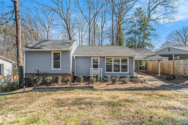 view of front facade with a carport, brick siding, a front lawn, and fence
