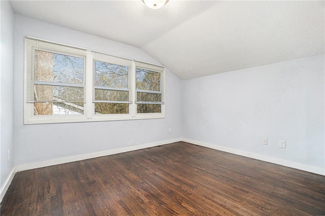 additional living space with vaulted ceiling, dark wood-style flooring, and baseboards