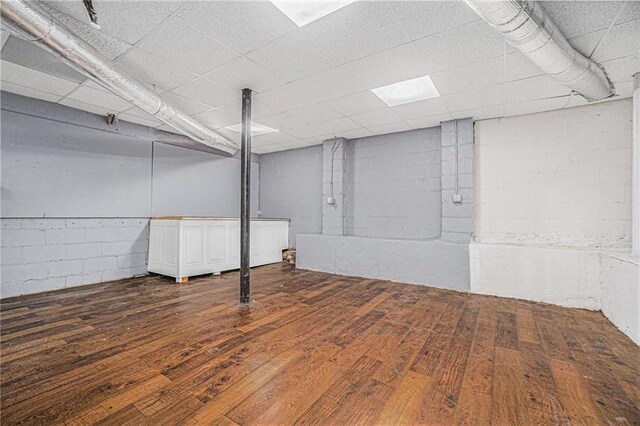 finished basement featuring concrete block wall and dark wood-style floors