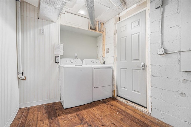 laundry room with concrete block wall, laundry area, washing machine and dryer, and dark wood-style floors
