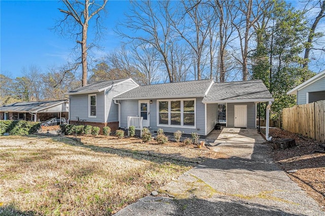 view of front of home featuring aphalt driveway, an attached carport, roof with shingles, fence, and a front lawn