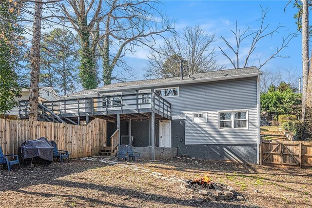rear view of property featuring an outdoor fire pit, fence, and a wooden deck