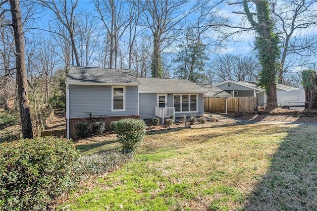 rear view of property with fence and a lawn