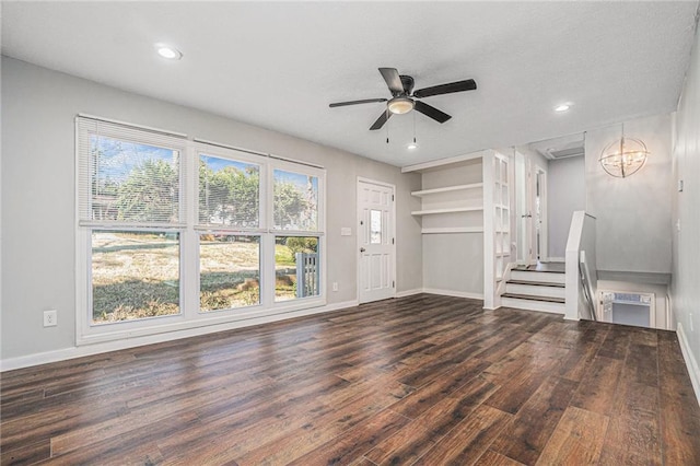 unfurnished living room with recessed lighting, dark wood finished floors, baseboards, and ceiling fan with notable chandelier