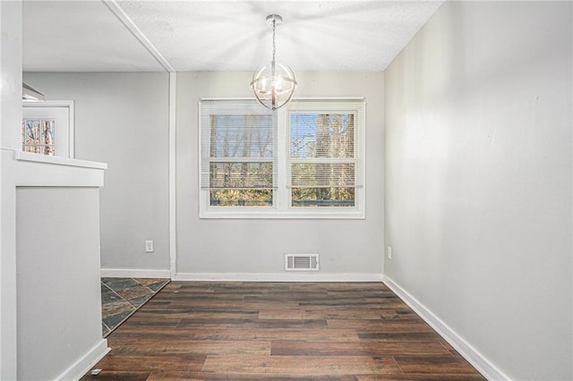 unfurnished dining area featuring a chandelier, dark wood-style flooring, visible vents, and baseboards