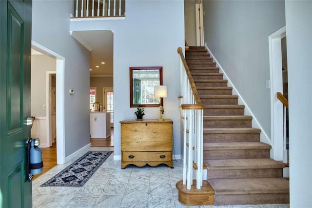 entrance foyer featuring crown molding, stairs, and baseboards