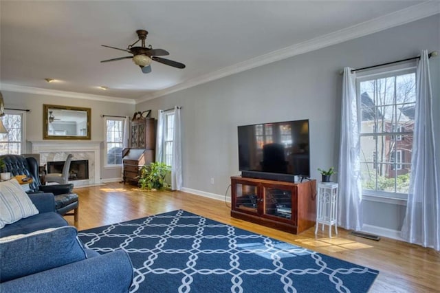 living room featuring a fireplace, crown molding, visible vents, wood finished floors, and baseboards