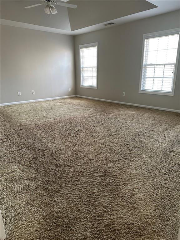 carpeted spare room with a tray ceiling and ceiling fan