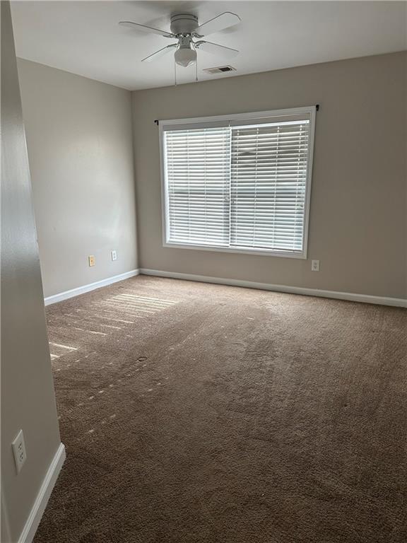 carpeted spare room with ceiling fan