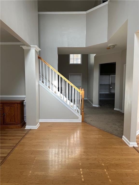 staircase with a high ceiling, ornamental molding, and hardwood / wood-style floors