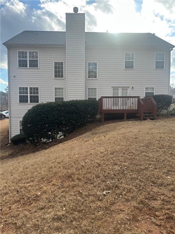 rear view of property with a wooden deck and a lawn