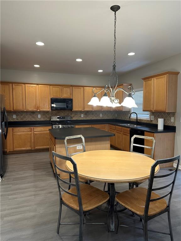 kitchen featuring sink, dark hardwood / wood-style flooring, hanging light fixtures, a center island, and black appliances