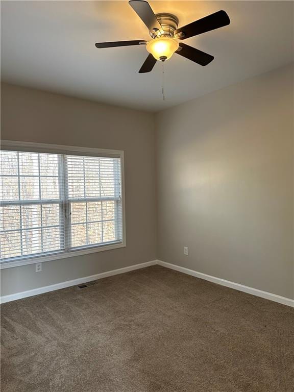 empty room with ceiling fan and dark colored carpet