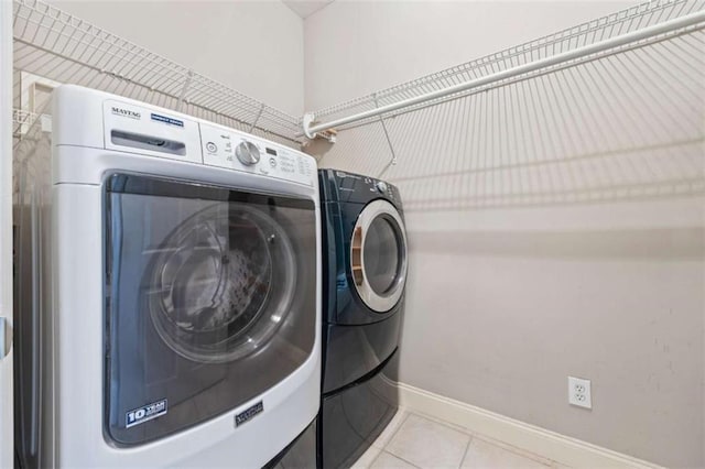 clothes washing area with independent washer and dryer and light tile patterned flooring