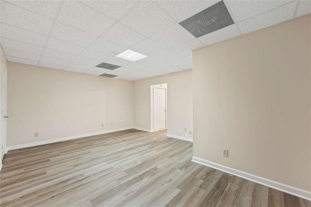 empty room featuring a drop ceiling and light wood-type flooring