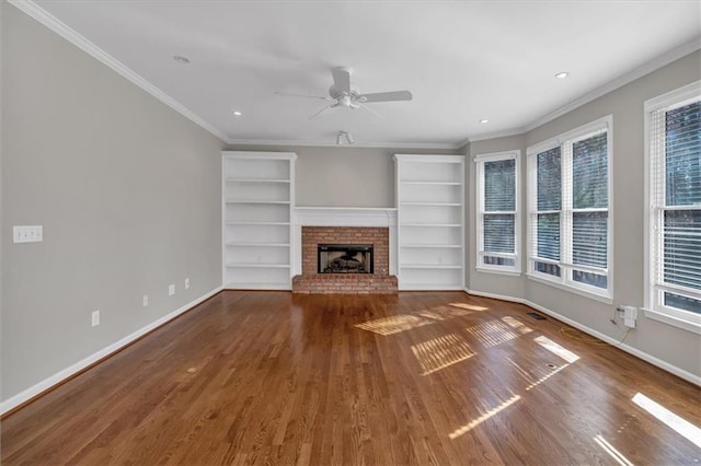 unfurnished living room with crown molding, a brick fireplace, dark hardwood / wood-style floors, and ceiling fan