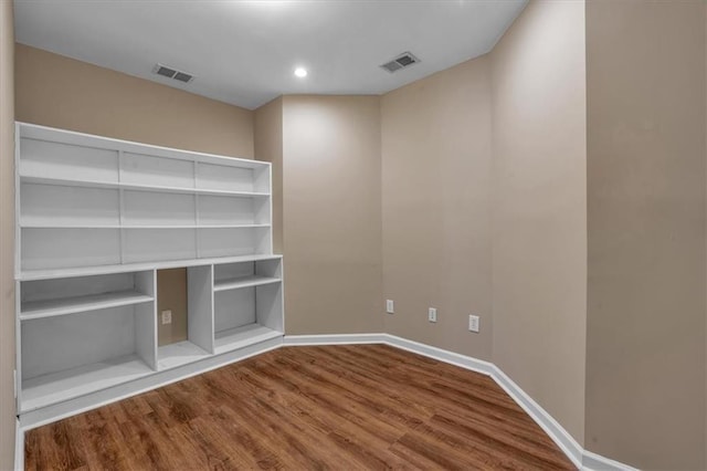 spare room featuring hardwood / wood-style flooring and built in shelves