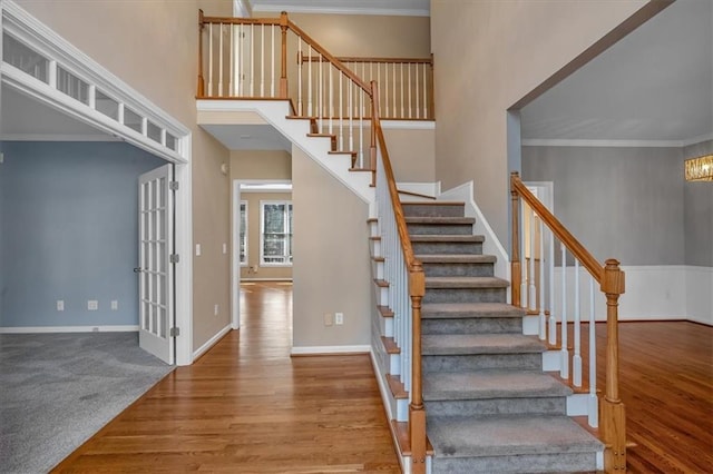 stairs featuring crown molding, a towering ceiling, and hardwood / wood-style floors