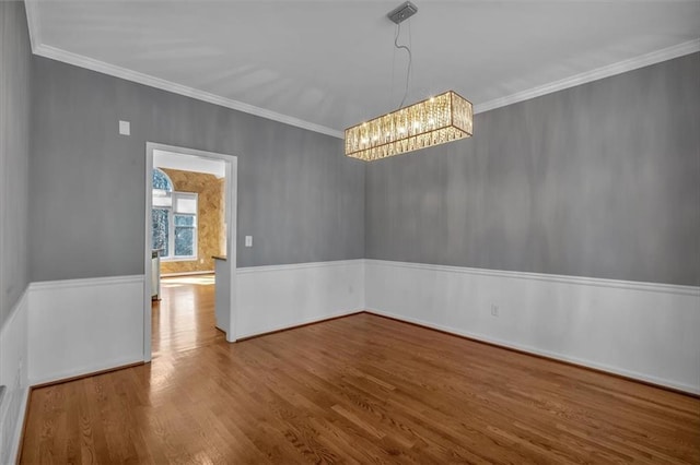 spare room with ornamental molding, a chandelier, and wood-type flooring