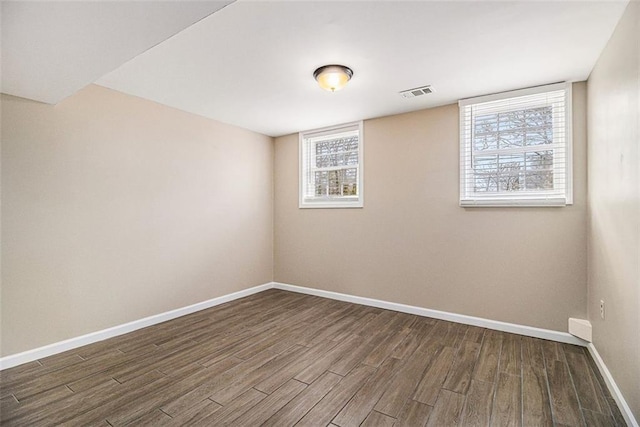 spare room with baseboards, visible vents, and wood finished floors