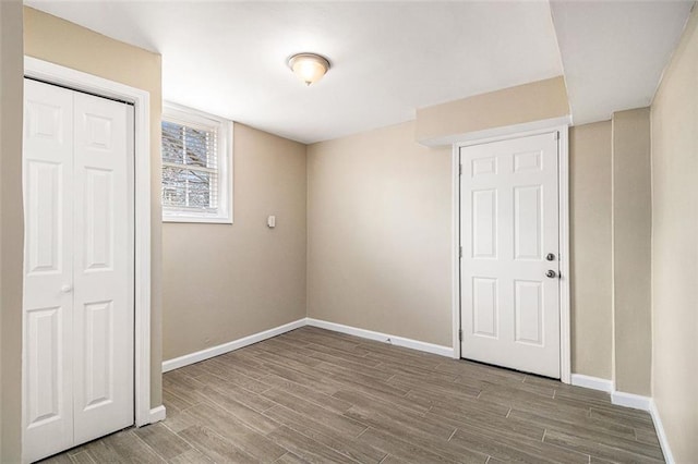 unfurnished bedroom with wood finish floors, a closet, and baseboards