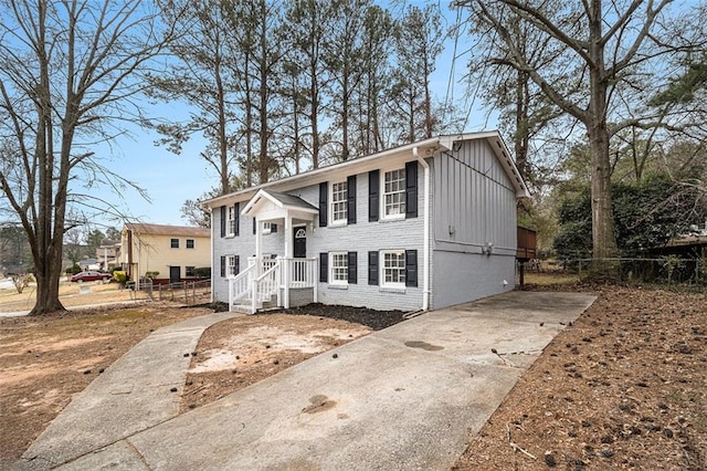 raised ranch featuring board and batten siding, brick siding, and fence