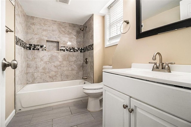 bathroom featuring visible vents, toilet, wood tiled floor, vanity, and  shower combination