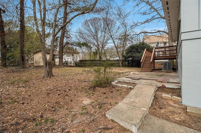 view of yard with a deck, a patio, cooling unit, fence, and stairway