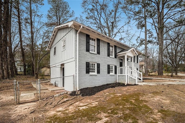 view of property exterior with board and batten siding, a gate, brick siding, and fence