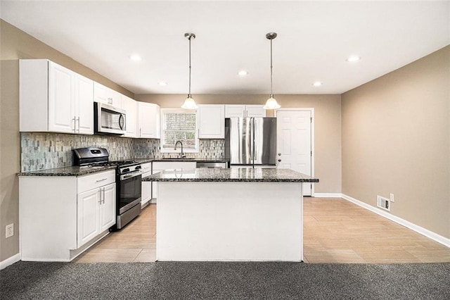 kitchen featuring stainless steel appliances, visible vents, white cabinets, backsplash, and a center island