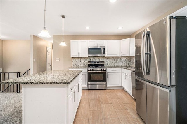 kitchen featuring tasteful backsplash, white cabinets, a kitchen island, stainless steel appliances, and stone counters