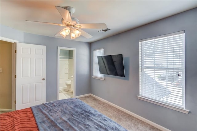 carpeted bedroom with a ceiling fan, visible vents, baseboards, and connected bathroom