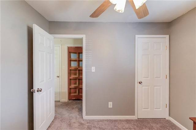 unfurnished bedroom featuring carpet floors, baseboards, and a ceiling fan