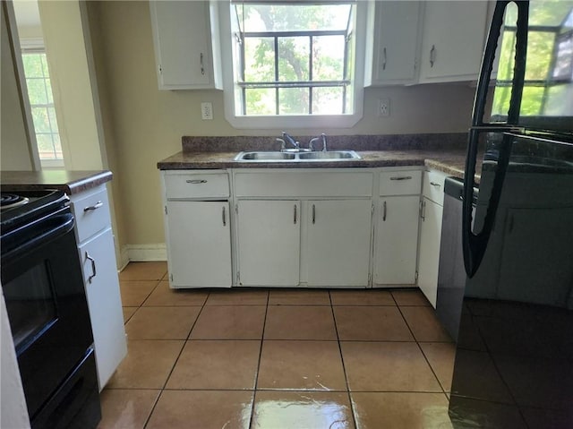 kitchen with white cabinets, black appliances, light tile patterned flooring, and sink