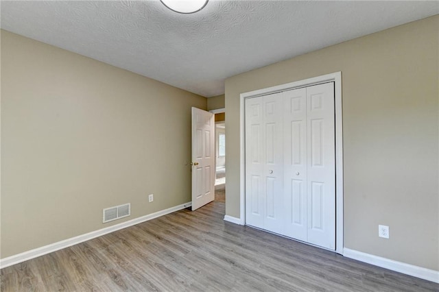 1400 Scenic Brook Trl SW, Conyers, GA 30094 - unfurnished bedroom with wood finished floors, baseboards, a closet, and a textured ceiling