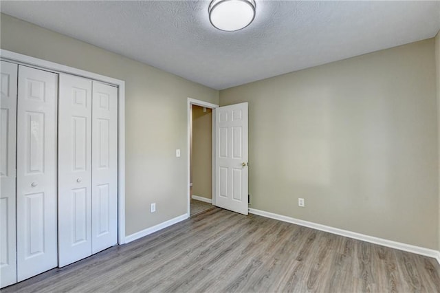 1400 Scenic Brook Trl SW, Conyers, GA 30094 - unfurnished bedroom featuring light wood-type flooring, baseboards, a closet, and a textured ceiling